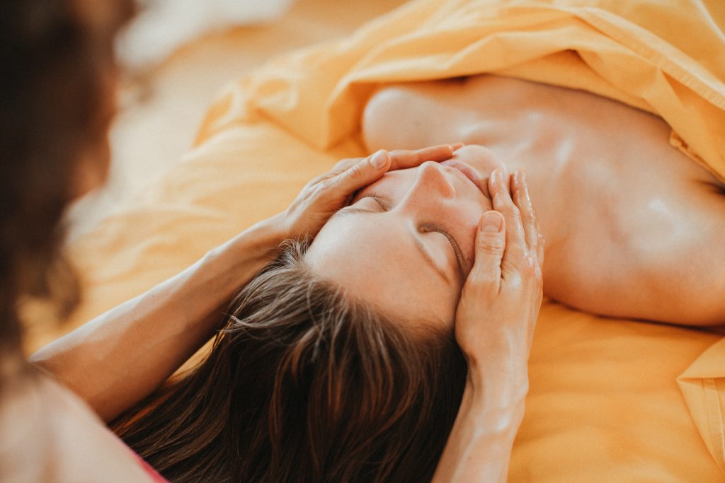 Massierende Hände berühren achtsam und liebevoll das Gesicht