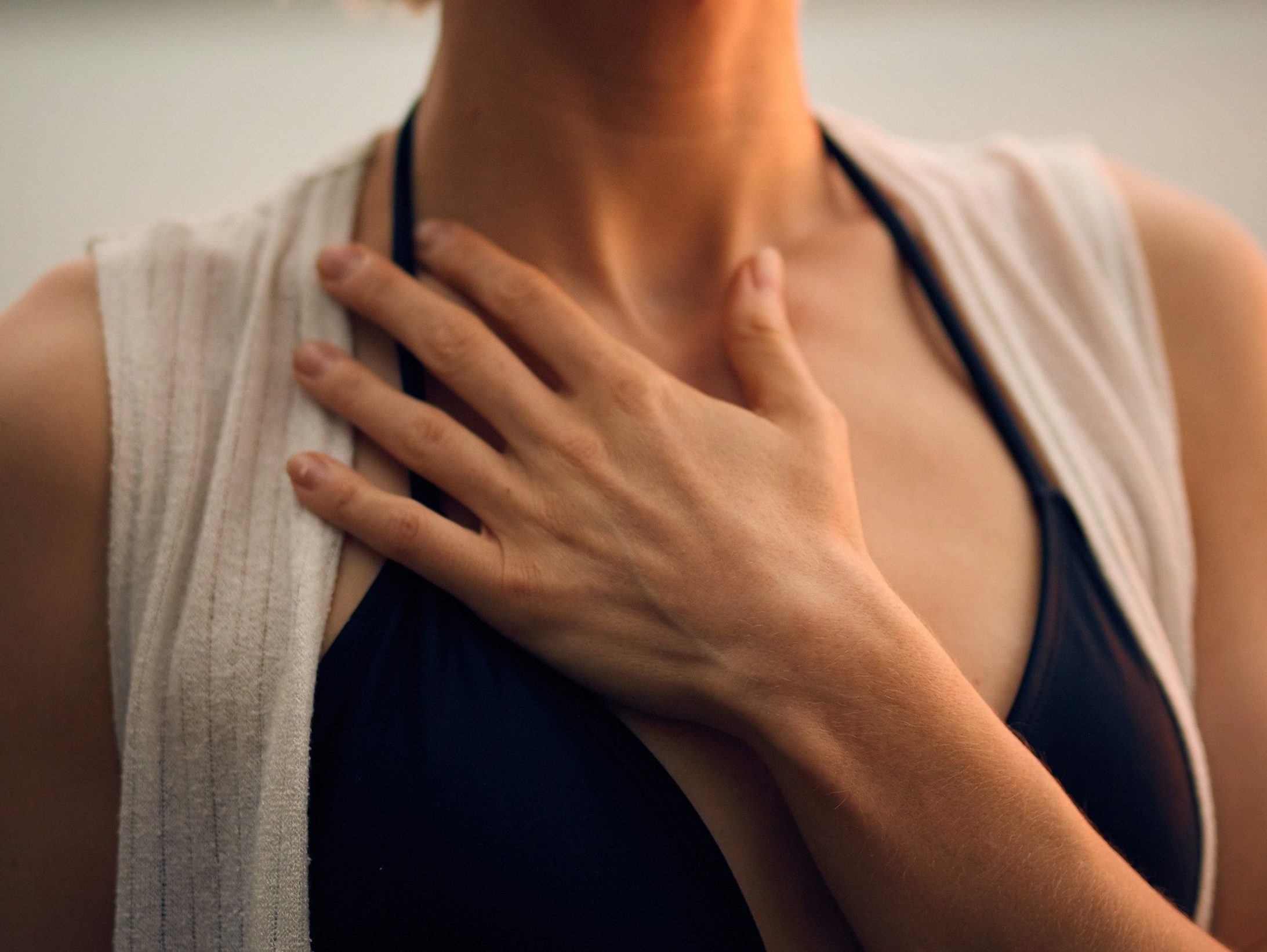 Eine Frau berührt sich achtsam im Brustbereich und lauscht ihrem Inneren Erleben beim Focusing-Coaching.